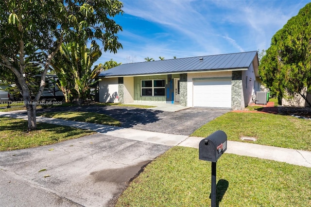 ranch-style home featuring a garage, central AC, and a front lawn