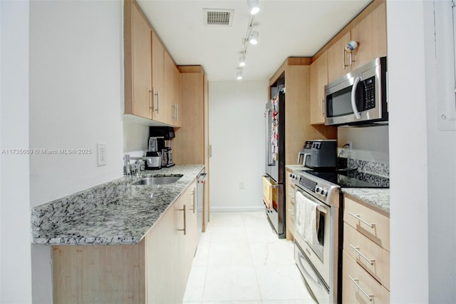 kitchen featuring sink, rail lighting, appliances with stainless steel finishes, light stone counters, and light brown cabinetry