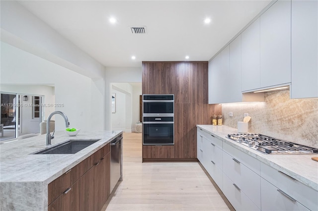 kitchen featuring white cabinetry, sink, light stone counters, and black appliances