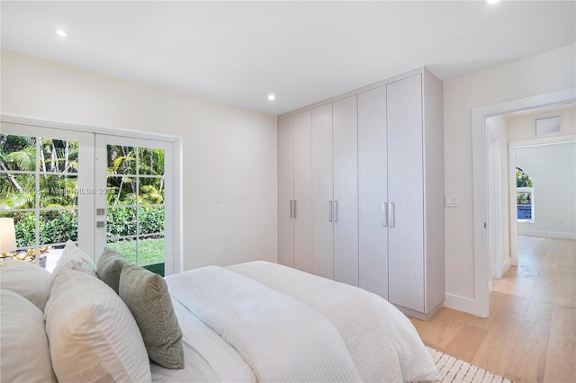 bedroom with french doors, light hardwood / wood-style floors, multiple windows, and access to outside