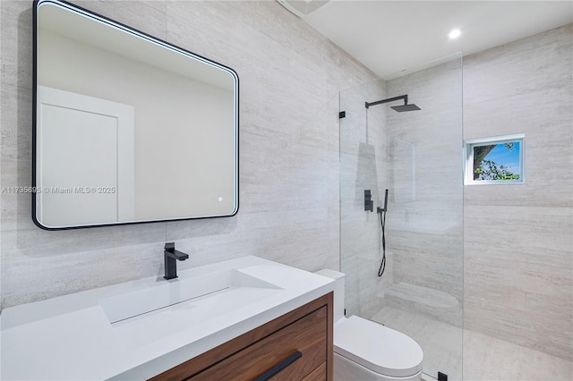 bathroom featuring tile walls, tiled shower, vanity, tasteful backsplash, and toilet