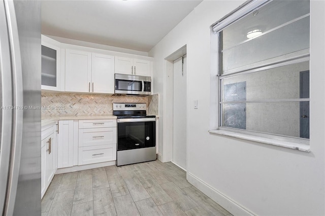 4050 NW 42nd Ave Unit 318, Fort Lauderdale, FL 33319 - kitchen with decorative backsplash, light hardwood / wood-style flooring, stainless steel appliances, and white cabinets
