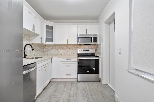 4050 NW 42nd Ave Unit 318, Fort Lauderdale, FL 33319 - kitchen featuring sink, appliances with stainless steel finishes, backsplash, light hardwood / wood-style floors, and white cabinets