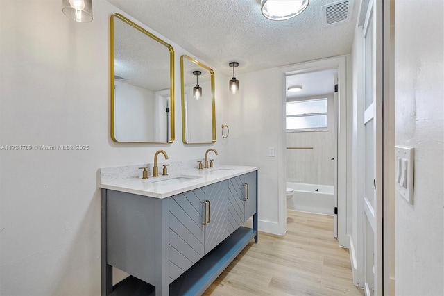 4050 NW 42nd Ave Unit 318, Fort Lauderdale, FL 33319 - full bathroom featuring toilet, wood-type flooring, tub / shower combination, a textured ceiling, and vanity