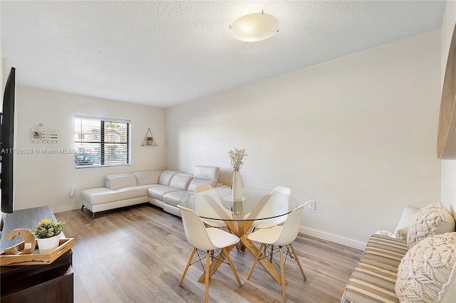 dining space with light hardwood / wood-style flooring and a textured ceiling