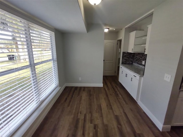 kitchen featuring tasteful backsplash, white cabinetry, light stone countertops, and dark hardwood / wood-style flooring