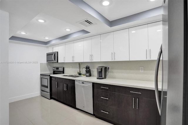 kitchen featuring sink, dark brown cabinets, stainless steel appliances, white cabinets, and a raised ceiling