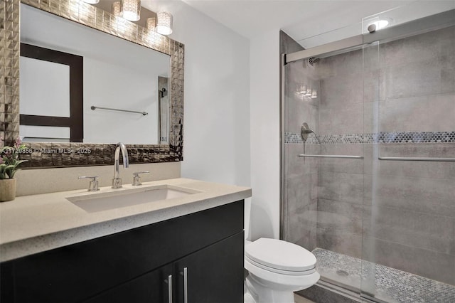 bathroom featuring vanity, an enclosed shower, and toilet