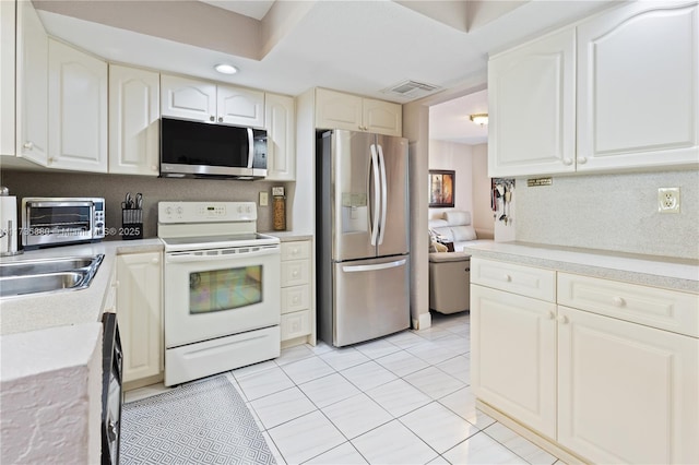 kitchen with light tile patterned floors, stainless steel appliances, sink, and white cabinets