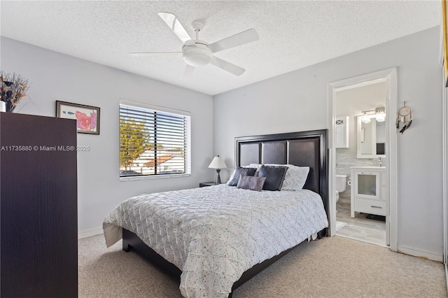 carpeted bedroom featuring ceiling fan, ensuite bath, and a textured ceiling