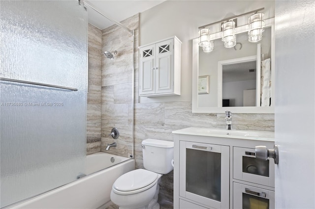 full bathroom with vanity, tile walls, bath / shower combo with glass door, and toilet