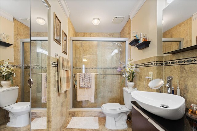 bathroom with toilet, crown molding, tile walls, vanity, and a shower with door