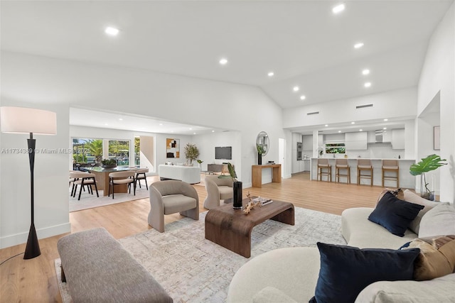 living room featuring high vaulted ceiling and light hardwood / wood-style floors