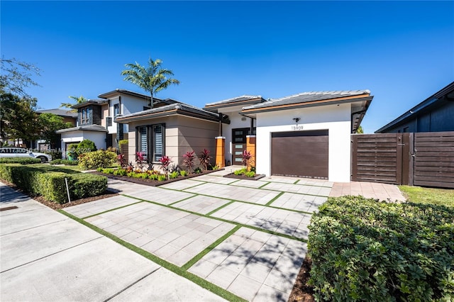 prairie-style house featuring a tile roof, driveway, an attached garage, and stucco siding