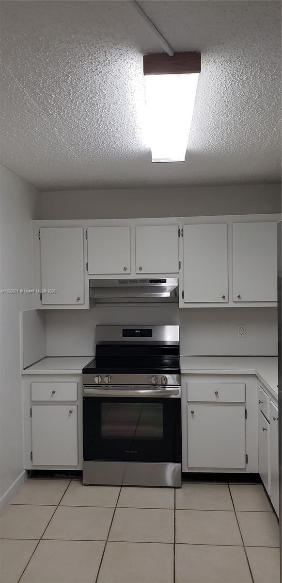 kitchen featuring under cabinet range hood, light tile patterned floors, light countertops, and electric stove