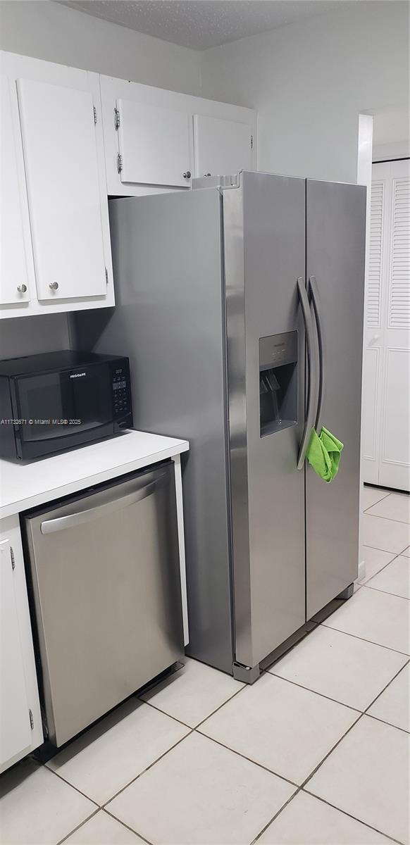 kitchen featuring light tile patterned floors, white cabinets, stainless steel appliances, and light countertops