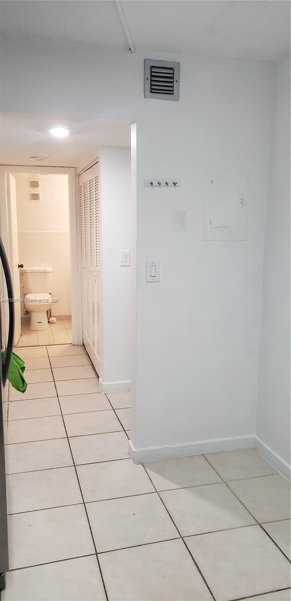 hallway featuring light tile patterned floors, baseboards, and visible vents