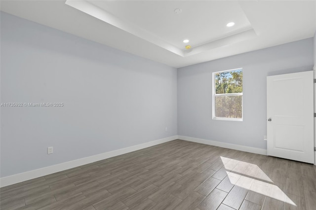 unfurnished room with hardwood / wood-style flooring and a tray ceiling