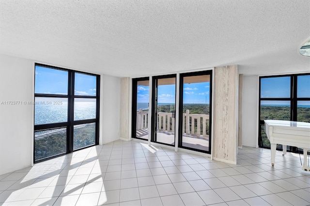 empty room with expansive windows, light tile patterned floors, and a textured ceiling