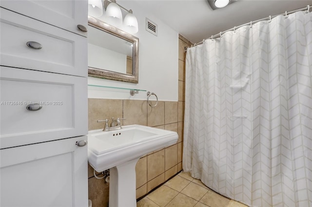 bathroom featuring tile patterned floors, curtained shower, and tile walls