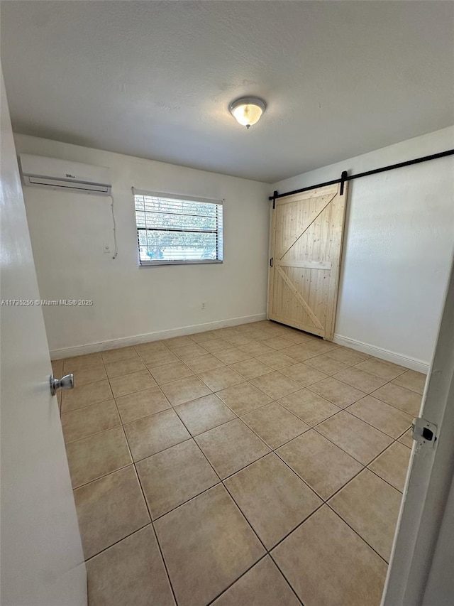 unfurnished bedroom with light tile patterned floors, a barn door, and a wall mounted AC