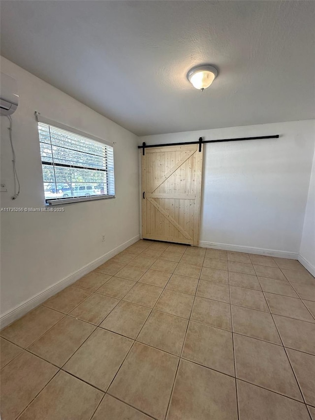 spare room with light tile patterned floors, a barn door, and a textured ceiling