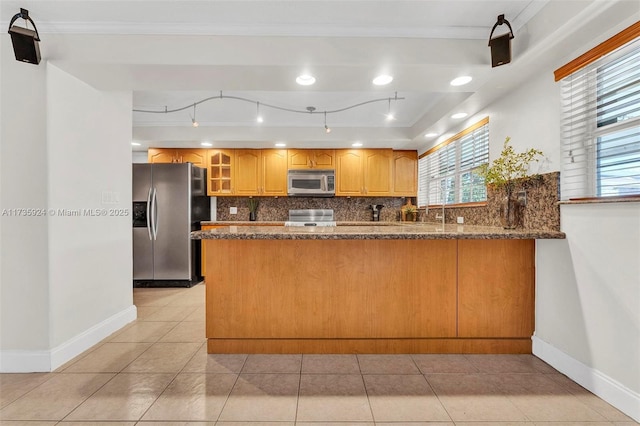 kitchen featuring light tile patterned floors, stainless steel appliances, decorative backsplash, kitchen peninsula, and dark stone counters