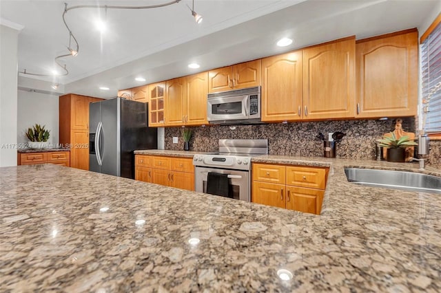 kitchen featuring sink, crown molding, stainless steel appliances, light stone countertops, and backsplash