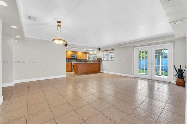 unfurnished living room with crown molding, light tile patterned floors, and french doors