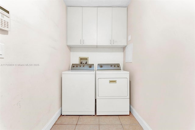 washroom featuring washing machine and dryer, cabinets, and light tile patterned flooring