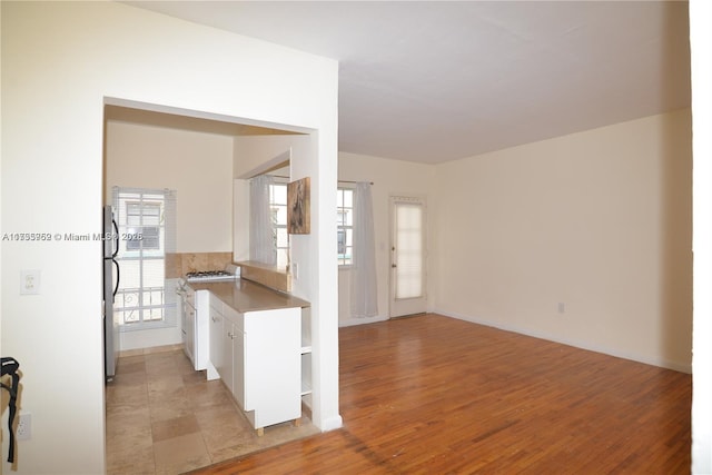 kitchen with white cabinetry, stainless steel fridge, and light wood-type flooring