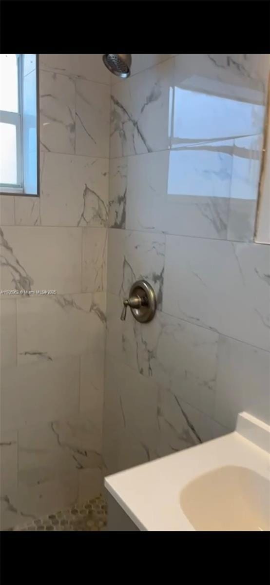 bathroom featuring tiled shower and sink