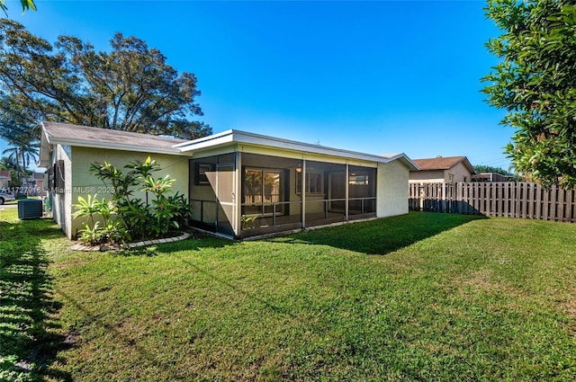 rear view of property with cooling unit, a lawn, and a sunroom