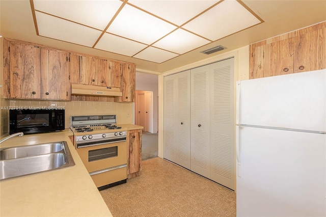 kitchen featuring tasteful backsplash, white fridge, sink, and range with gas stovetop