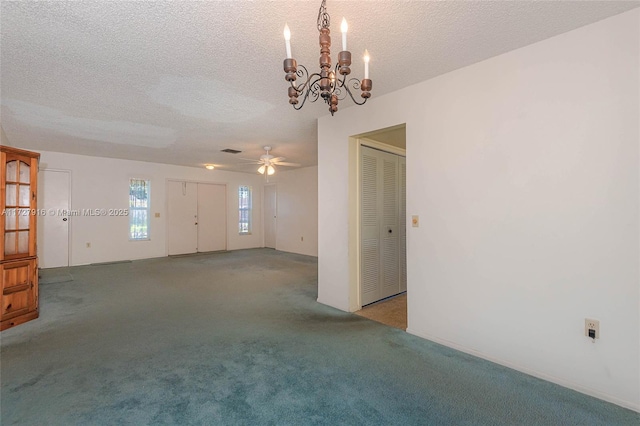 carpeted spare room with a chandelier and a textured ceiling