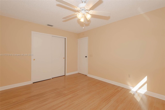 unfurnished bedroom featuring ceiling fan, a closet, a textured ceiling, and light wood-type flooring