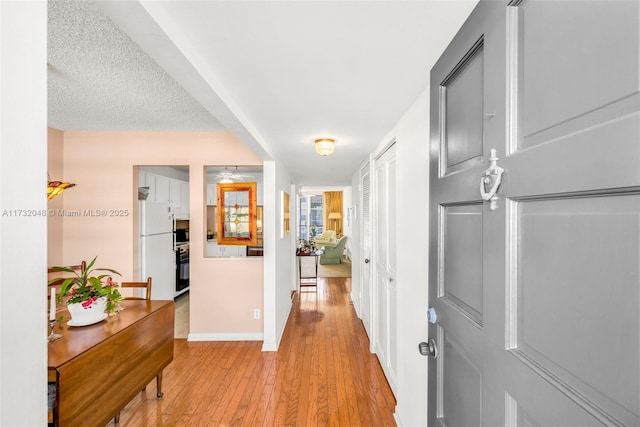 corridor with light wood-style floors and baseboards