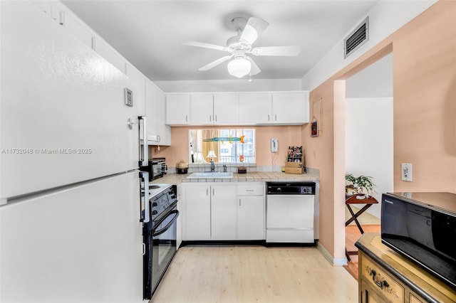 kitchen featuring visible vents, light wood-style floors, white appliances, white cabinetry, and a sink