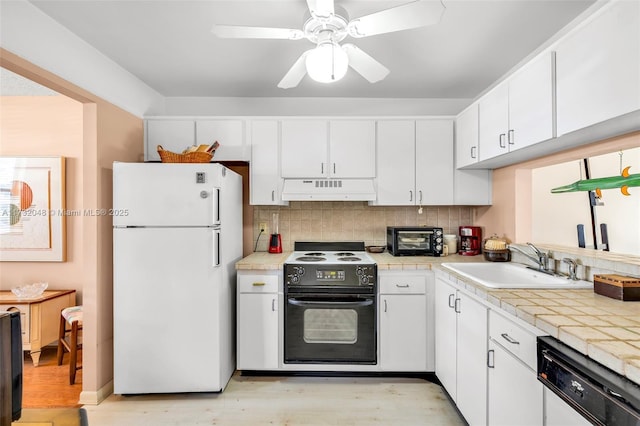 kitchen with white appliances, light wood-style floors, under cabinet range hood, and a sink