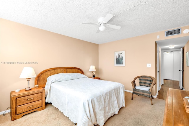 bedroom featuring ceiling fan, light carpet, and a textured ceiling