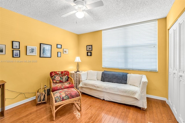 living room with wood-type flooring, ceiling fan, and a textured ceiling