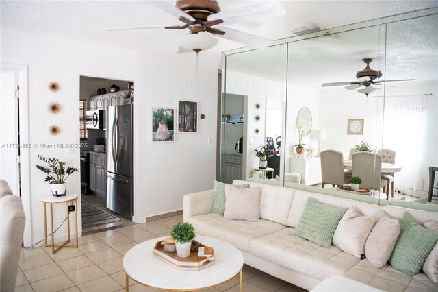 living room with ceiling fan, tile patterned floors, and a textured ceiling