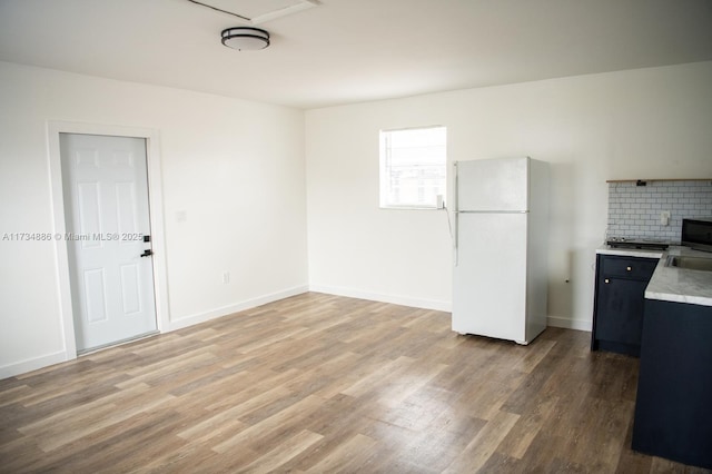 kitchen featuring hardwood / wood-style flooring, tasteful backsplash, and white fridge