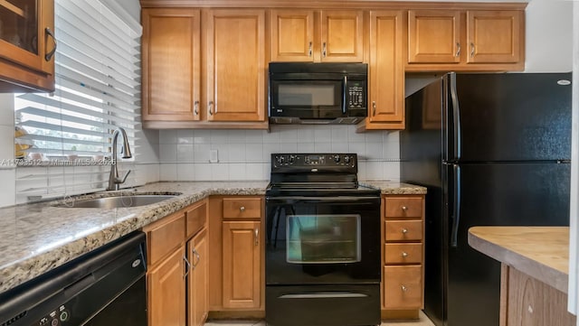 kitchen featuring tasteful backsplash, sink, light stone counters, and black appliances