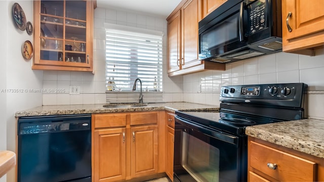 kitchen with tasteful backsplash, light stone countertops, sink, and black appliances