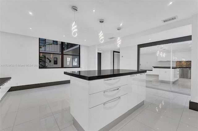 kitchen featuring a large island, light tile patterned floors, hanging light fixtures, and white cabinets