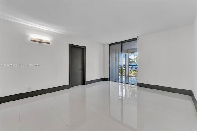 tiled empty room featuring a wall of windows