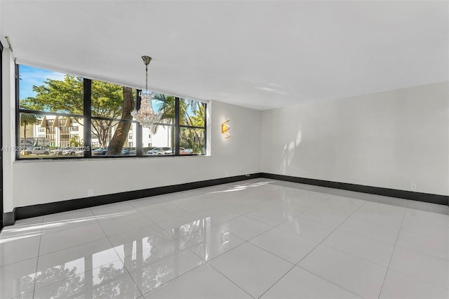 empty room featuring an inviting chandelier and light tile patterned floors