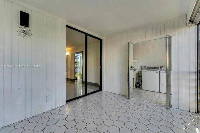 unfurnished room featuring washer and dryer and wood walls