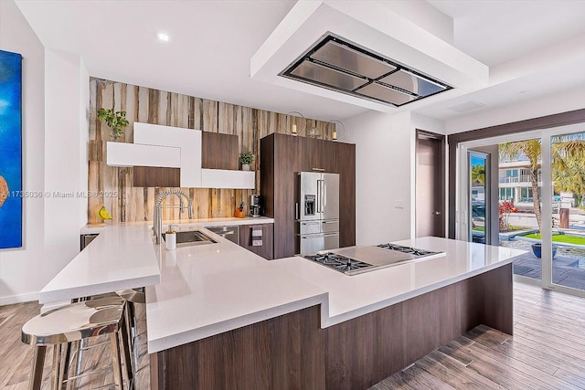 kitchen with a kitchen breakfast bar, kitchen peninsula, sink, and stainless steel appliances